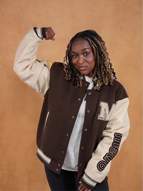 A model in a brown and cream Metro varsity jacket, arm flexed.