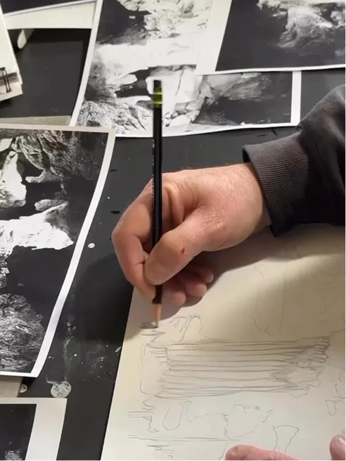 Hands sketching a cave formation in pencil, black-and-white reference photos alongside.