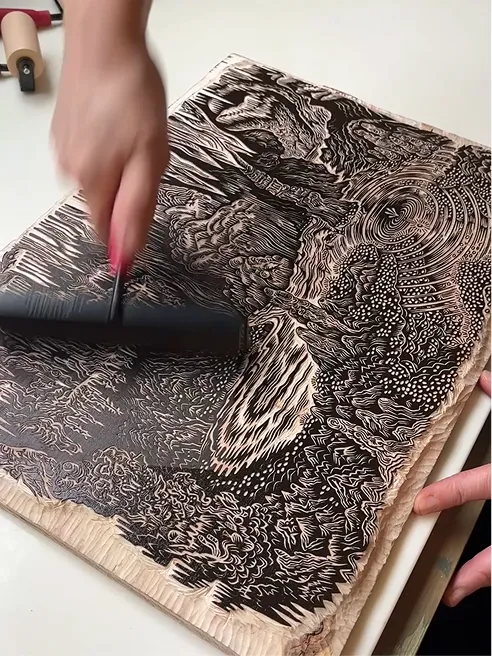 A brayer rolling ink across the finished woodblock.
