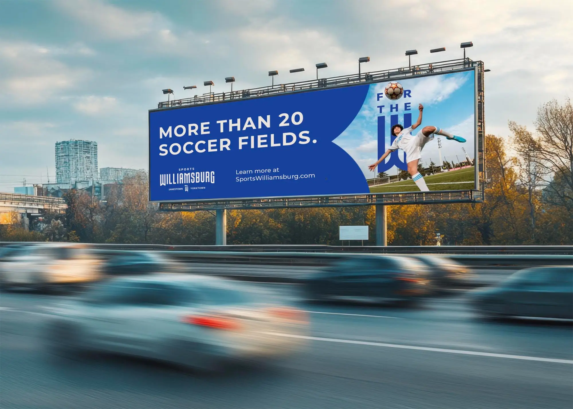 Highway billboard reading 'More than 20 soccer fields.' beside the soccer key visual, with the Sports Williamsburg logo and SportsWilliamsburg.com. Traffic blurs past below.